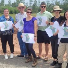 Sandra Moore and the team at the Cleantech Academy build site in Georgetown hold renderings of the future Cleantech Park